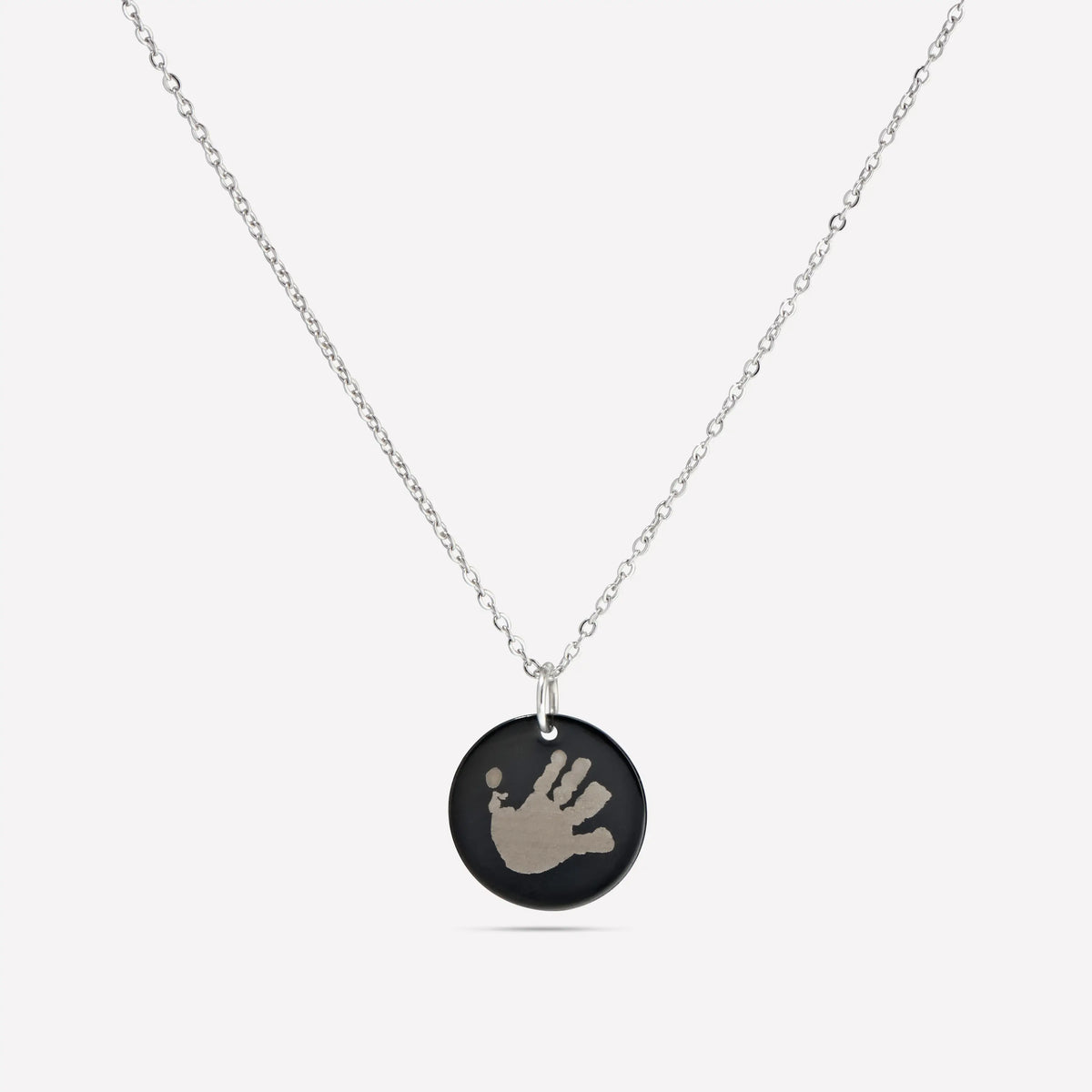 Black disc pendant necklace engraved with a child's handprint