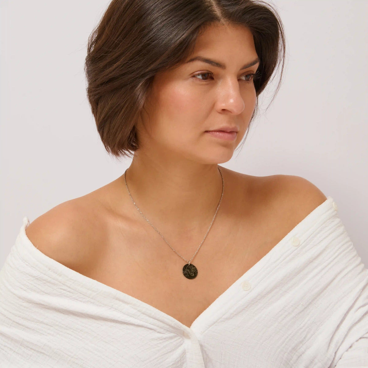 Woman in a white top wearing a black engraved street map necklace