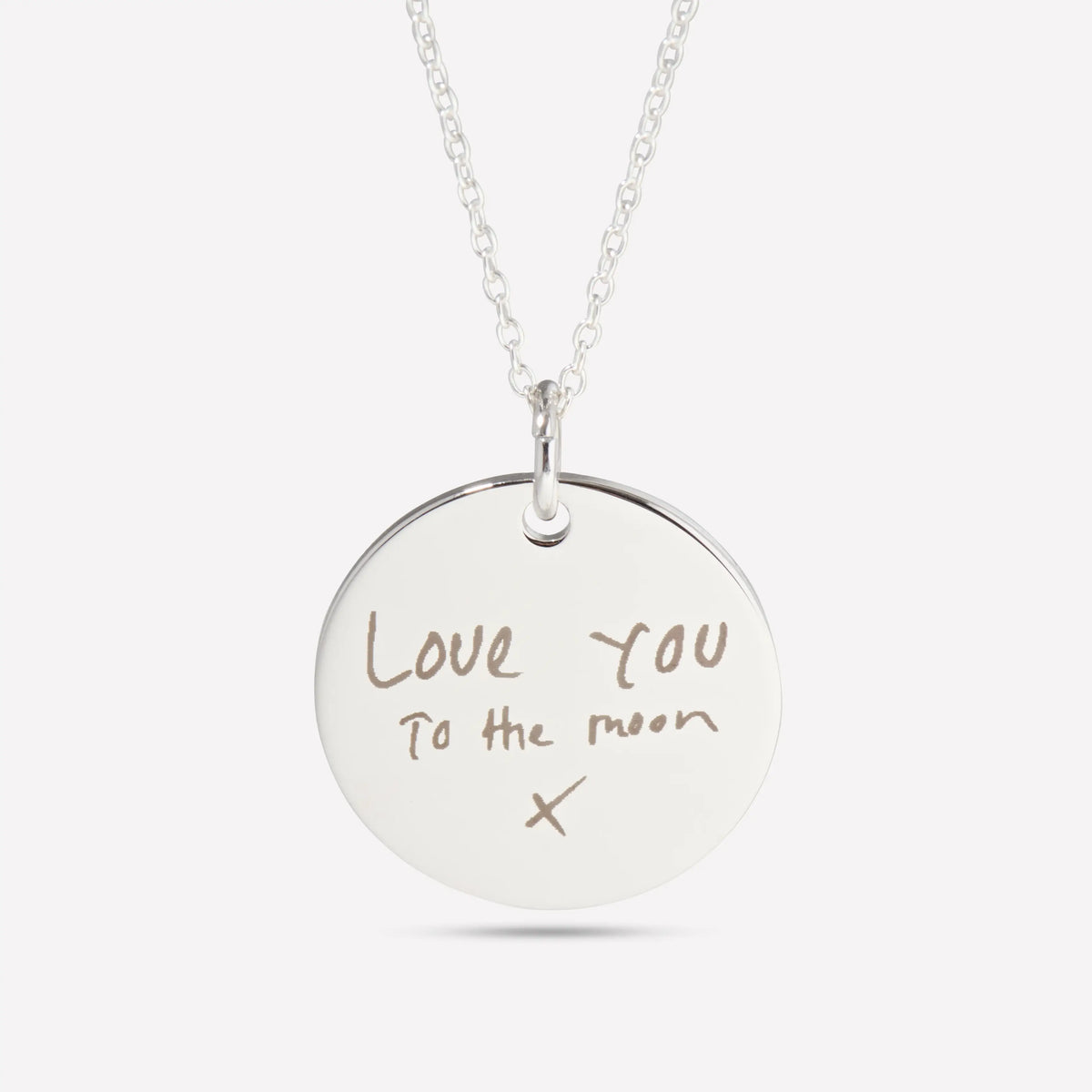 Close-up of a silver pendant engraved with the handwritten words Love you to the moon