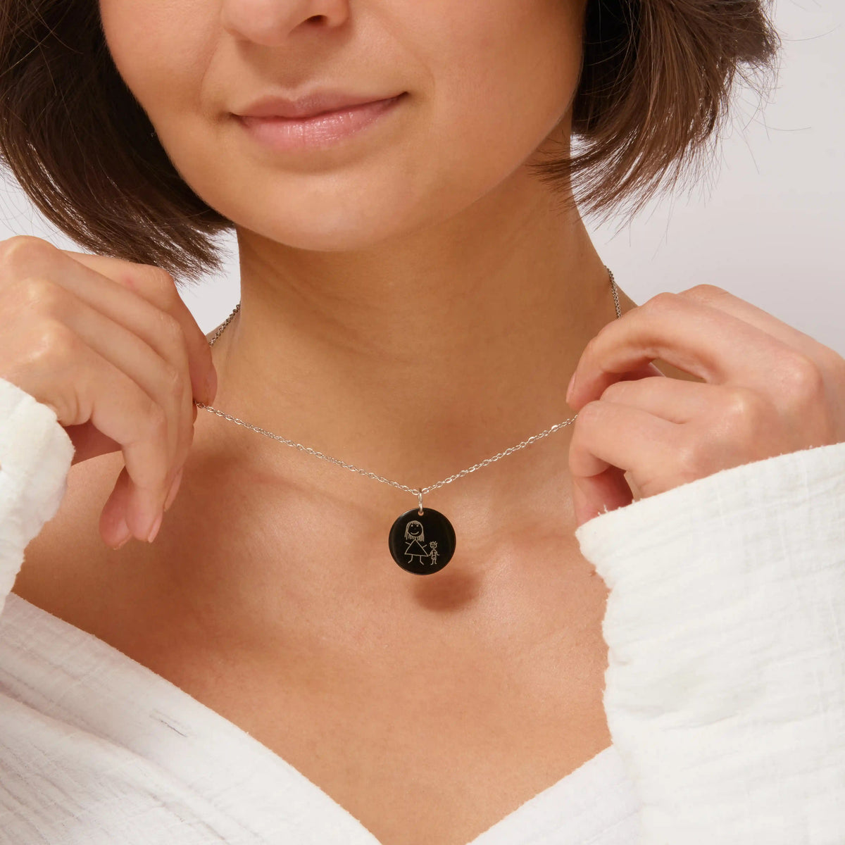 Woman holding a black children's drawing pendant necklace