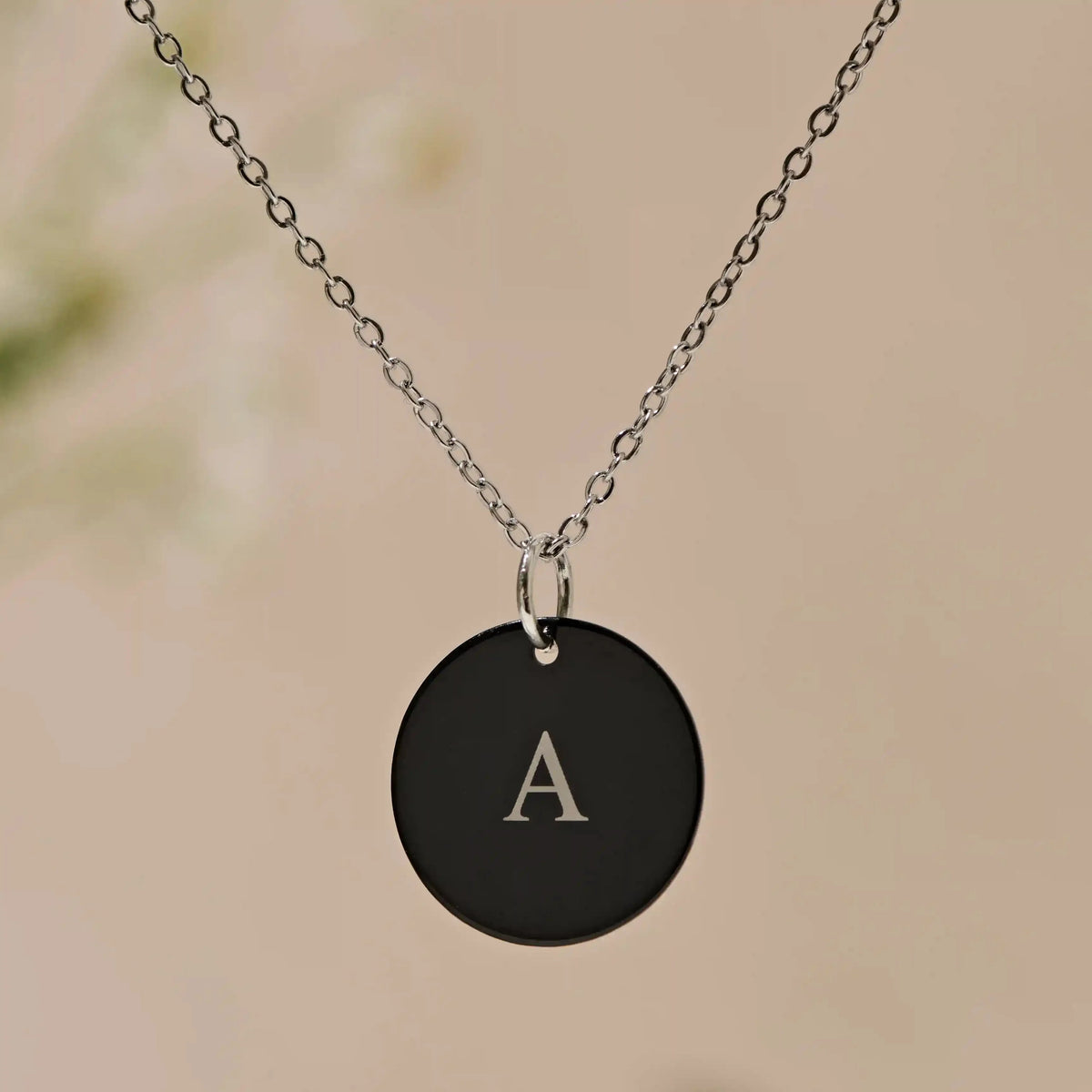 Black disc pendant necklace engraved with the initial A