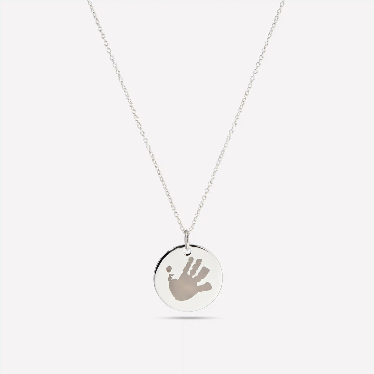 Silver disc pendant necklace engraved with a small handprint