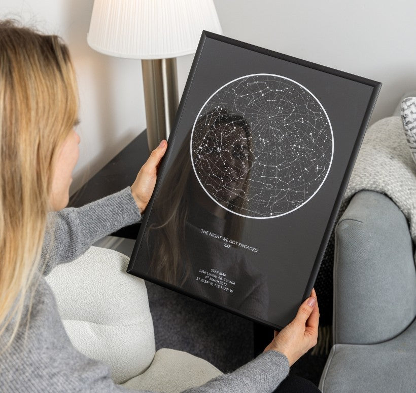 Couple looking at a navy star map print hung with a wooden hanger on the wall