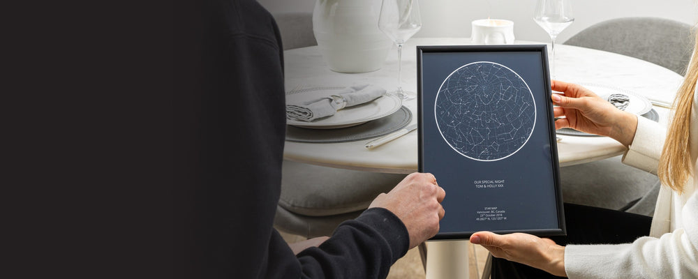 Couple at dinner holding a framed star map