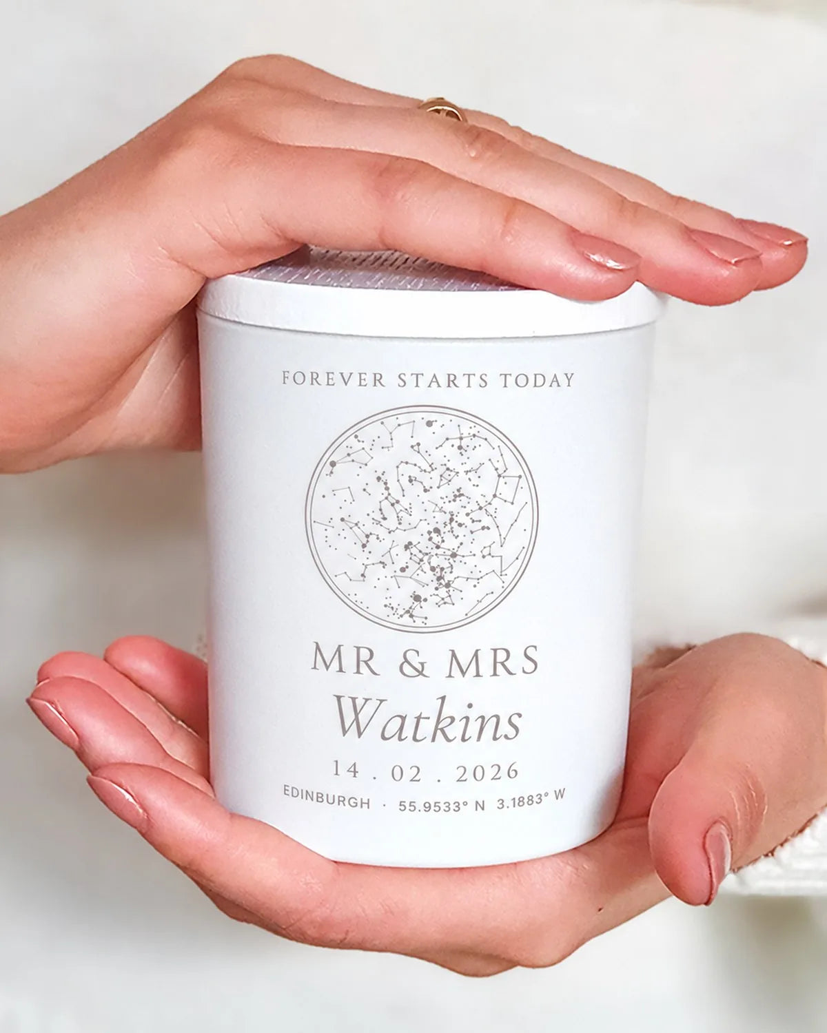 Hands holding a white engraved wedding candle with a star map and the couple's names
