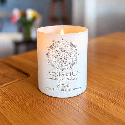 Lit engraved star map candle, birthday zodiac design, glowing on a table