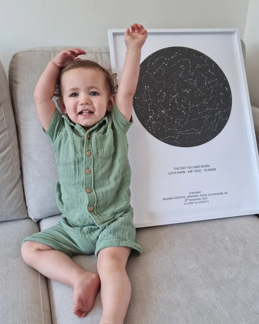 Toddler cheering beside a white framed star map