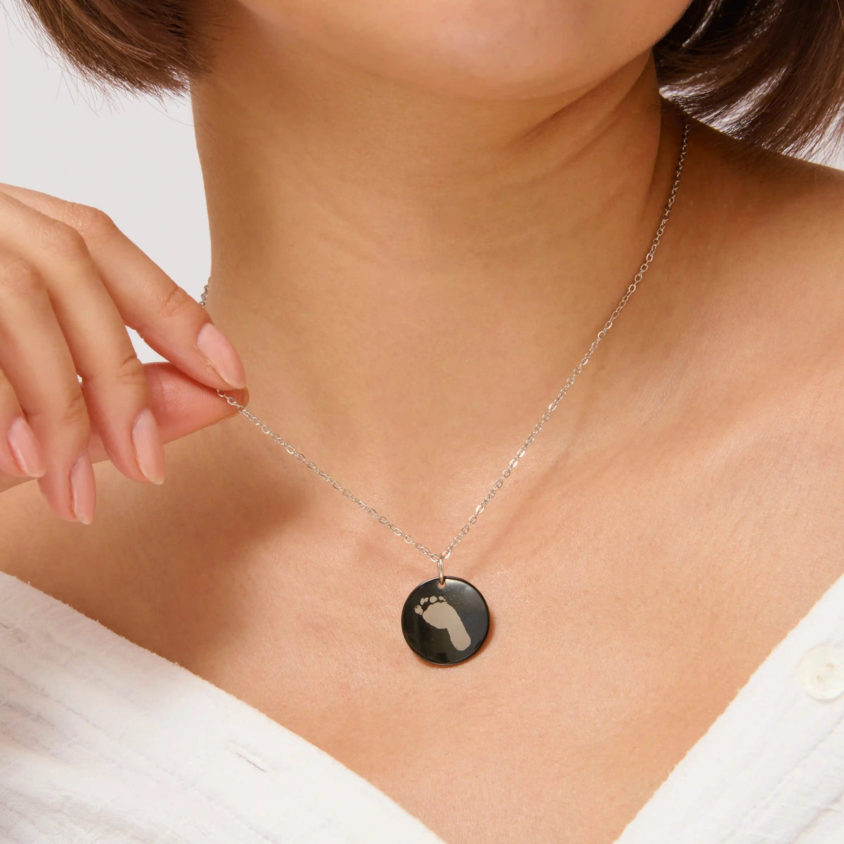 Woman wearing a black baby footprint pendant necklace