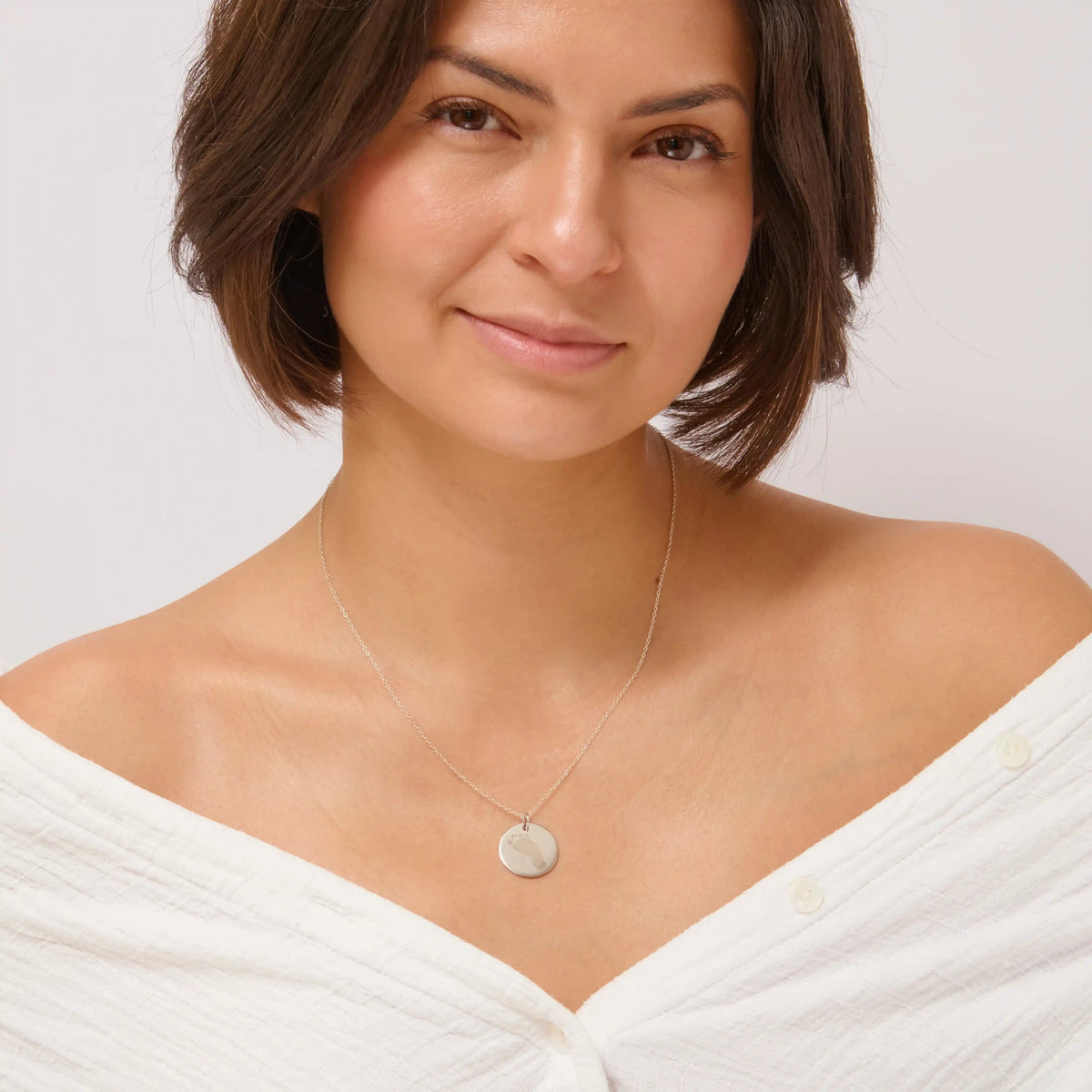Woman wearing a silver baby footprint pendant necklace