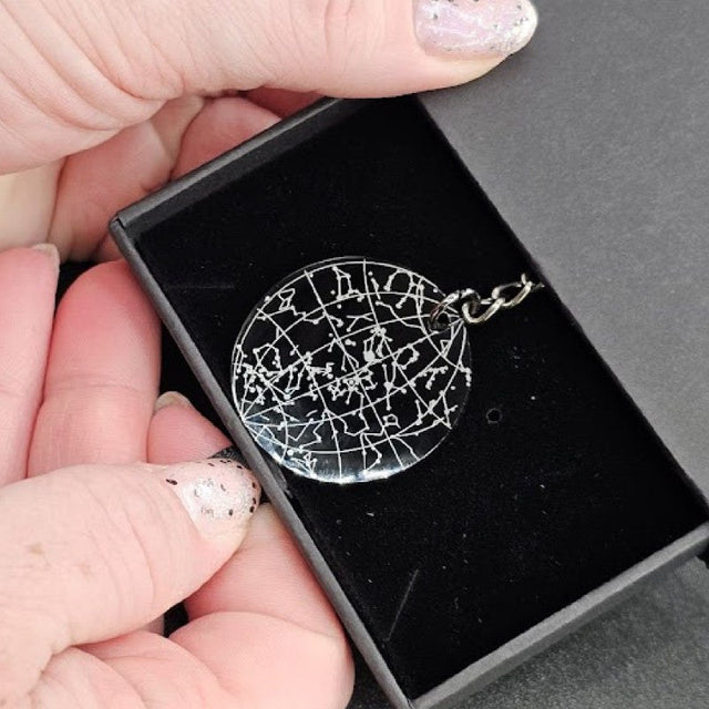 Engraved star map keychain held in a hand