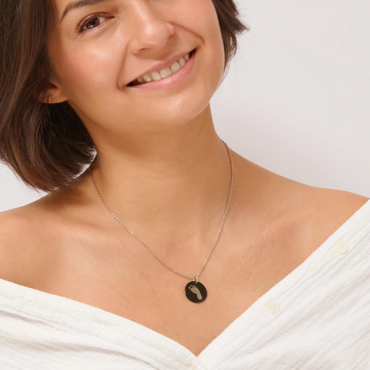 Woman wearing a black footprint pendant necklace