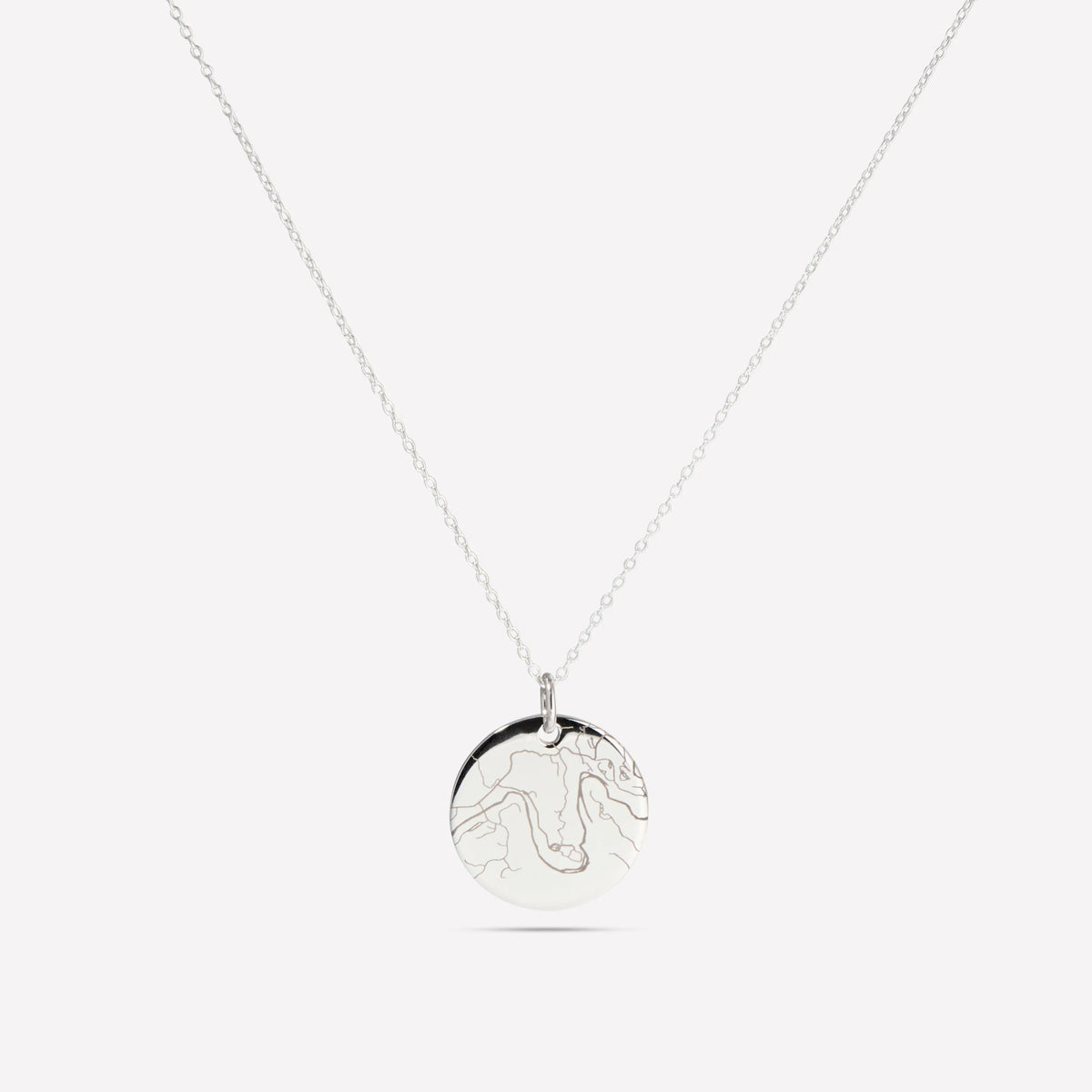 Silver street map disc pendant on a fine chain against a white background
