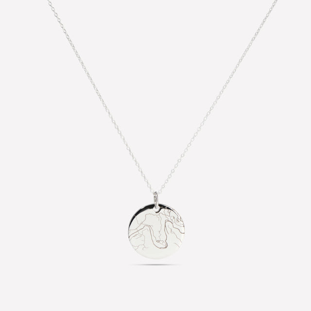 Silver street map disc pendant on a fine chain against a white background