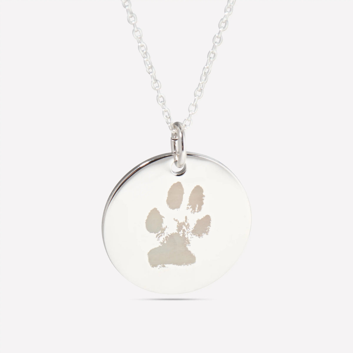 Close-up of a silver pendant engraved with a pet paw print
