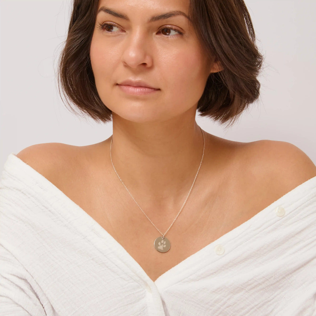 Woman wearing a silver paw print pendant necklace