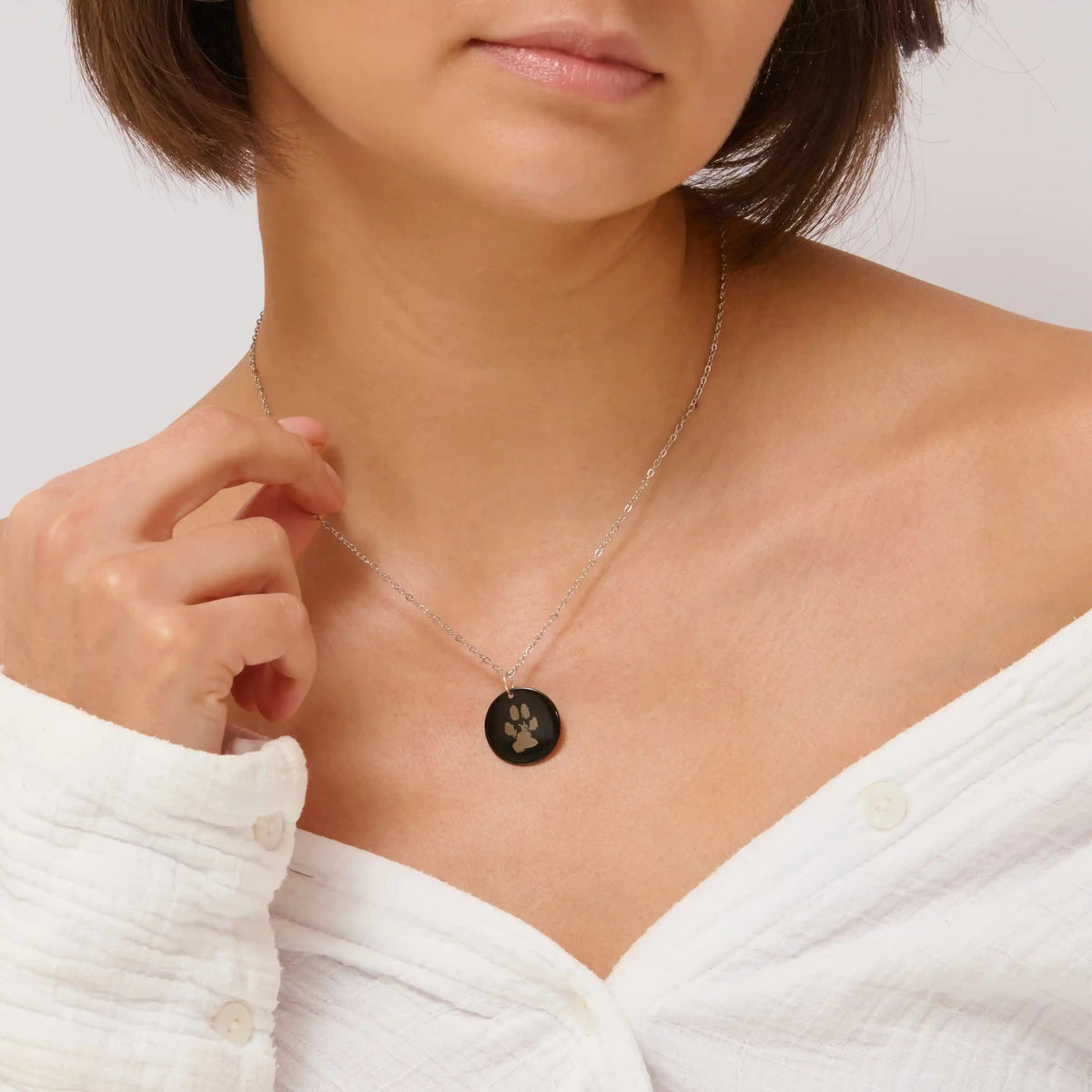 Woman wearing a black paw print pendant necklace
