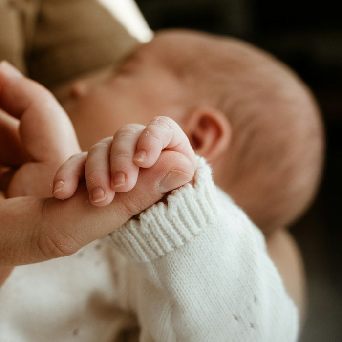 Newborn baby's hand holding an adult's finger