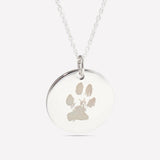 Close-up of a silver pendant engraved with a pet's paw print