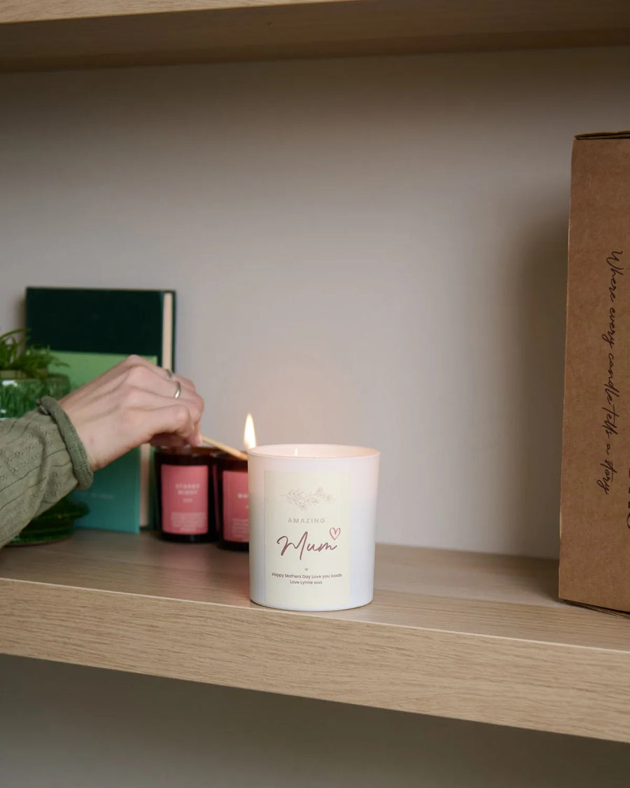 Hand lighting a white personalised candle on a wooden shelf
