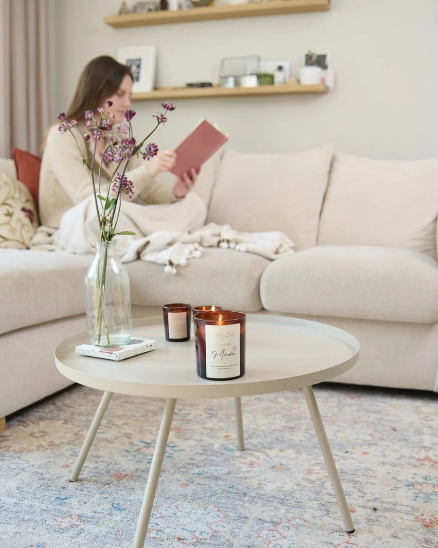 Woman reading on a sofa with a lit candle on the coffee table