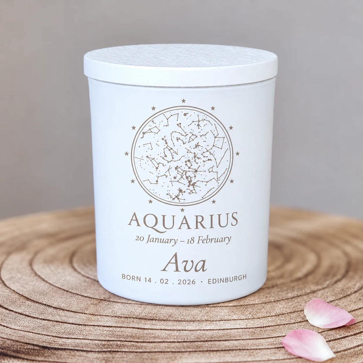 Engraved star map candle in a white glass jar, birthday zodiac design personalised with the Aquarius constellation for Ava, born 14.02.2026, on a wooden slice with petals