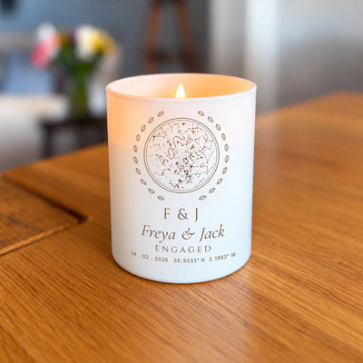 Lit engraved star map candle, engagement initials design, glowing on a table