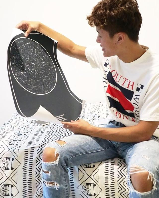 Young man unrolling a black star map print