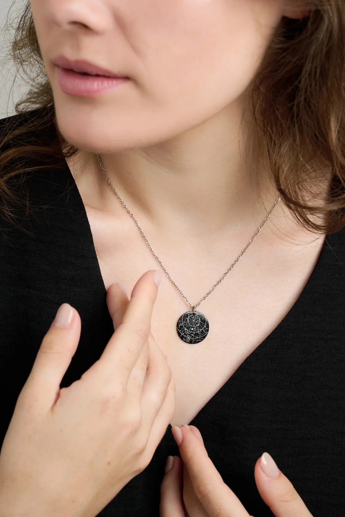 Woman touching her black star map pendant necklace