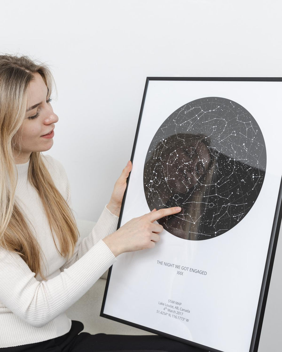 Woman pointing at constellations on a framed star map