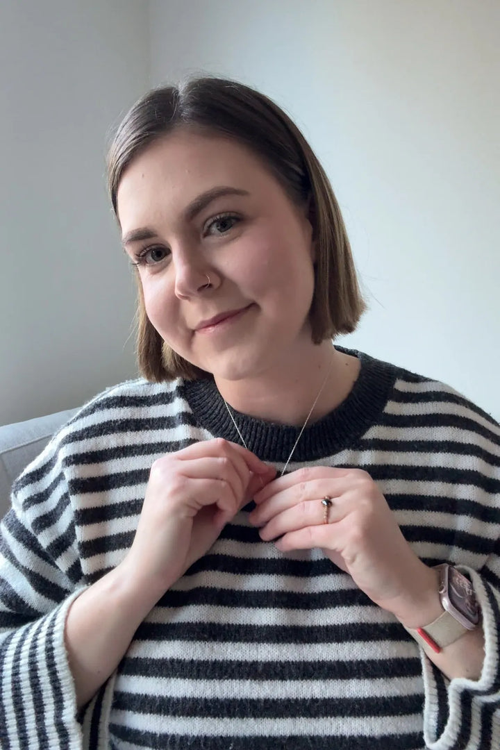 Une femme sourit en portant son pendentif étoile.