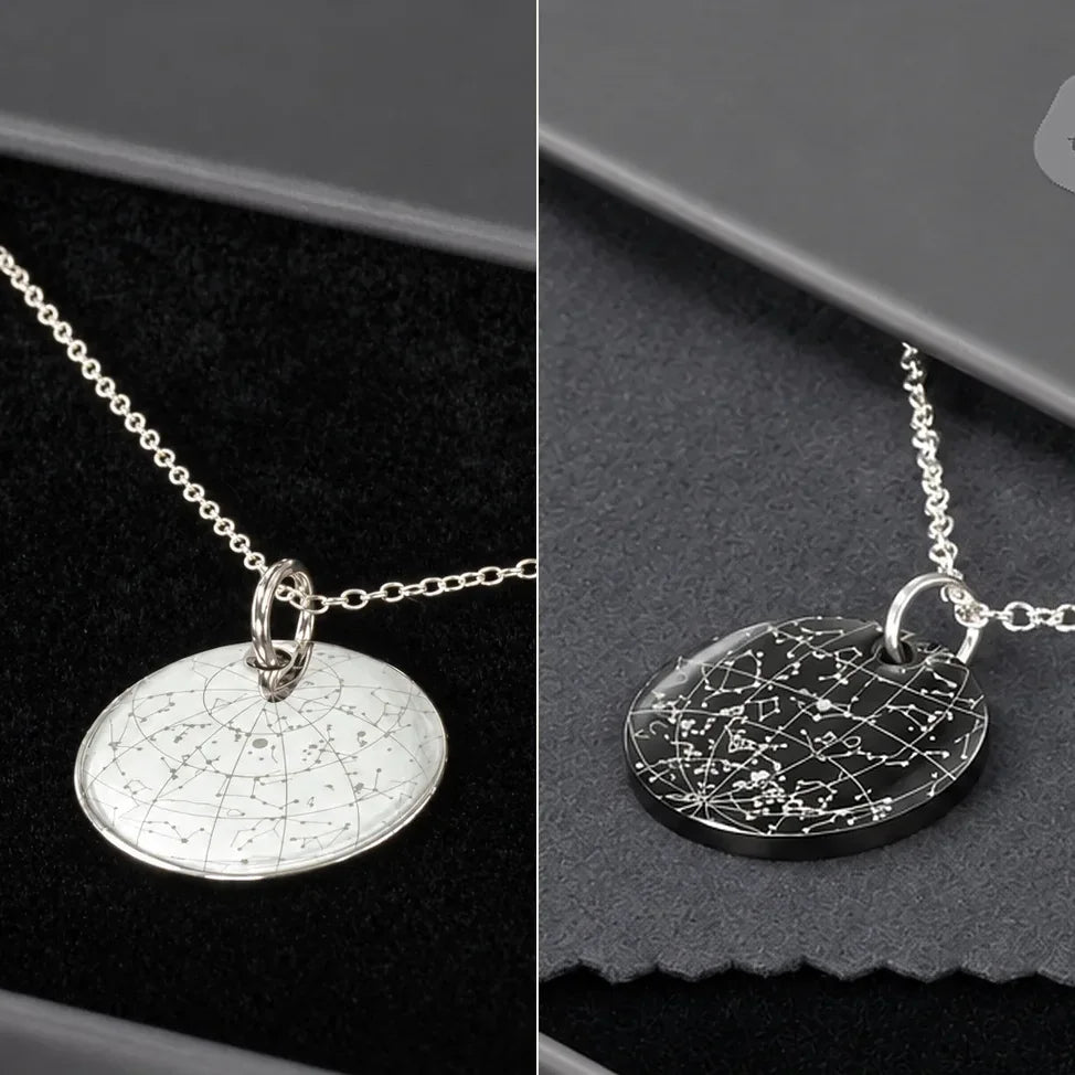 Silver and black engraved star map pendants on black and grey fabric in their gift box