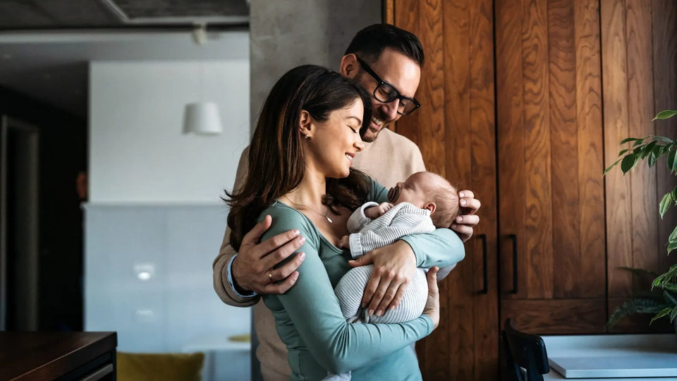 New parents holding their baby beside a star gift